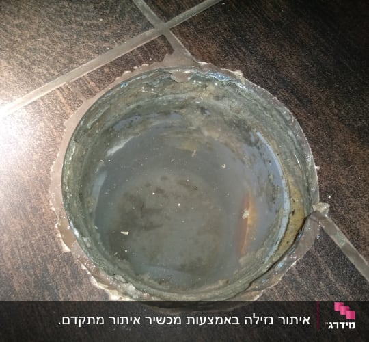 פתח ניקוז עם מים עומדים על רצפה כהה